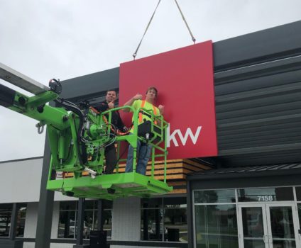 Two Ortwein Sign installers giving thumbs up after installing sign