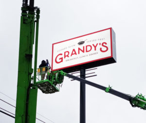 Grandy's Sign being installed with worker in crane bucket