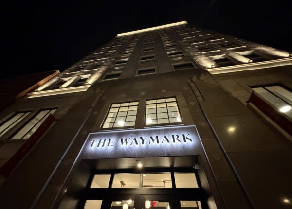 Custom entryway signage fabricated by Ortwein Sign as seen in a night photo of the facade of The Waymark hotel in downtown Chattanooga lit up at night